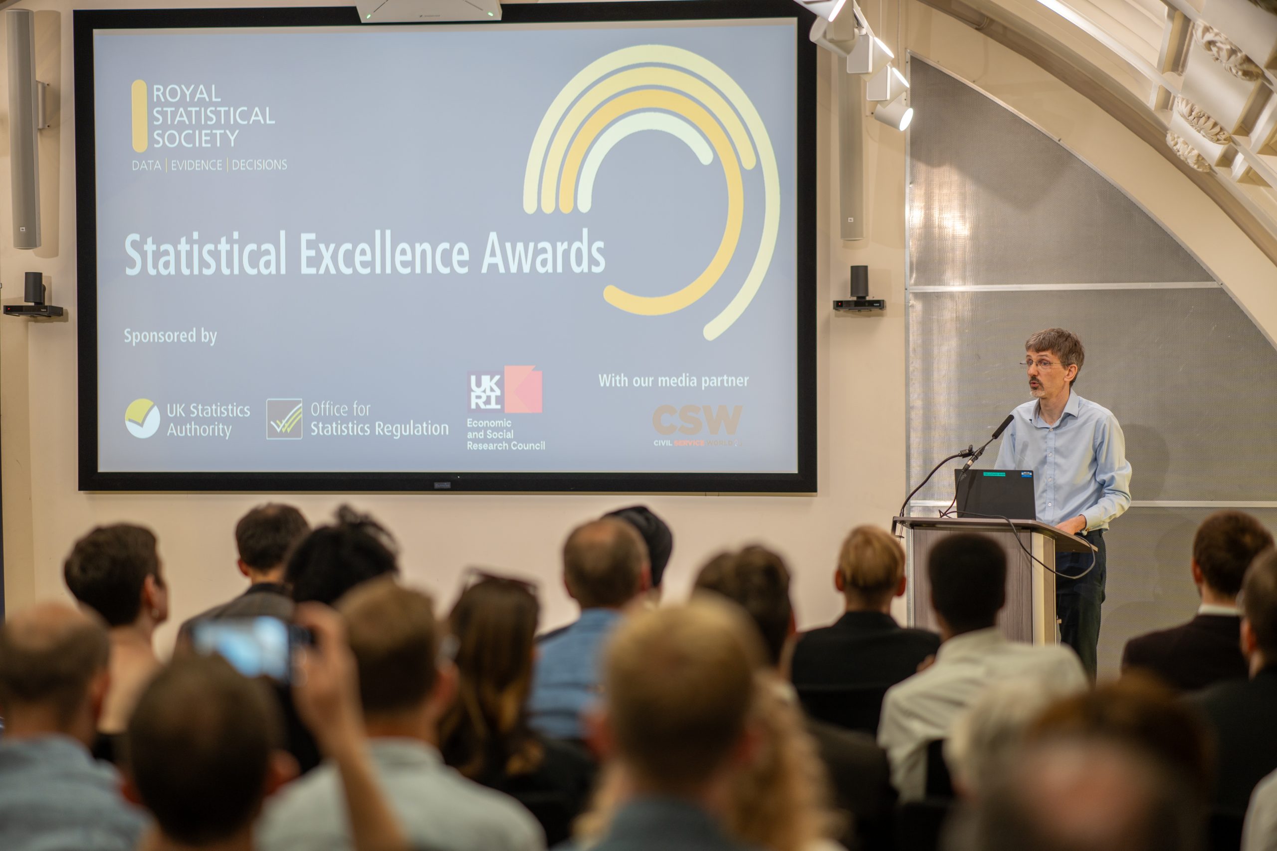 Audience watching a man speak at a lectern at an awards ceremony