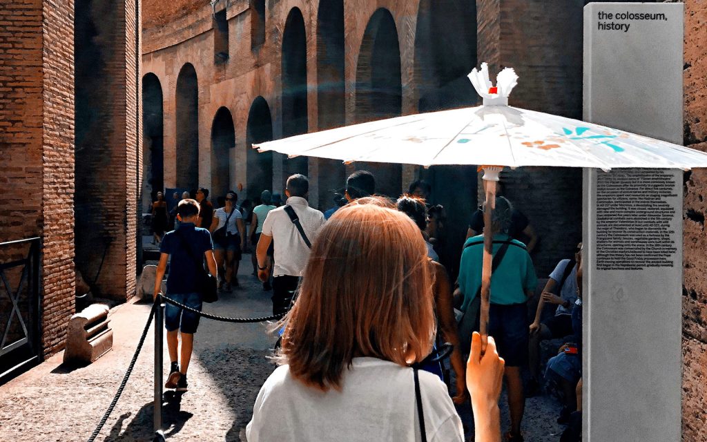 Girl in white T-shirt viewed from behind, carrying parasol and walking through Colosseum in Rome with other tourists on sunny day