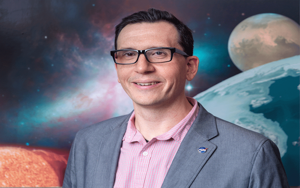 Smiling man standing in front of backdrop of planets