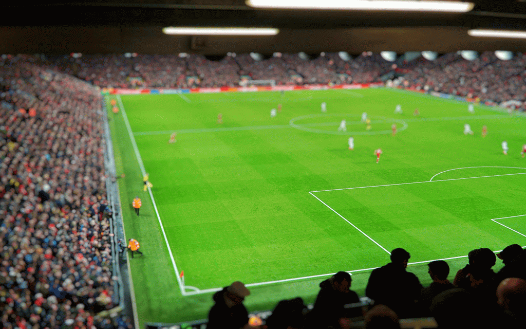 Inside of a football stadium showing pitch with players