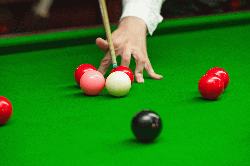 Snooker table showing player's hand and several snooker balls