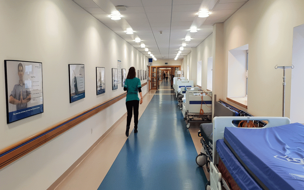 Nurse seen from behind walking down long hospital corridor